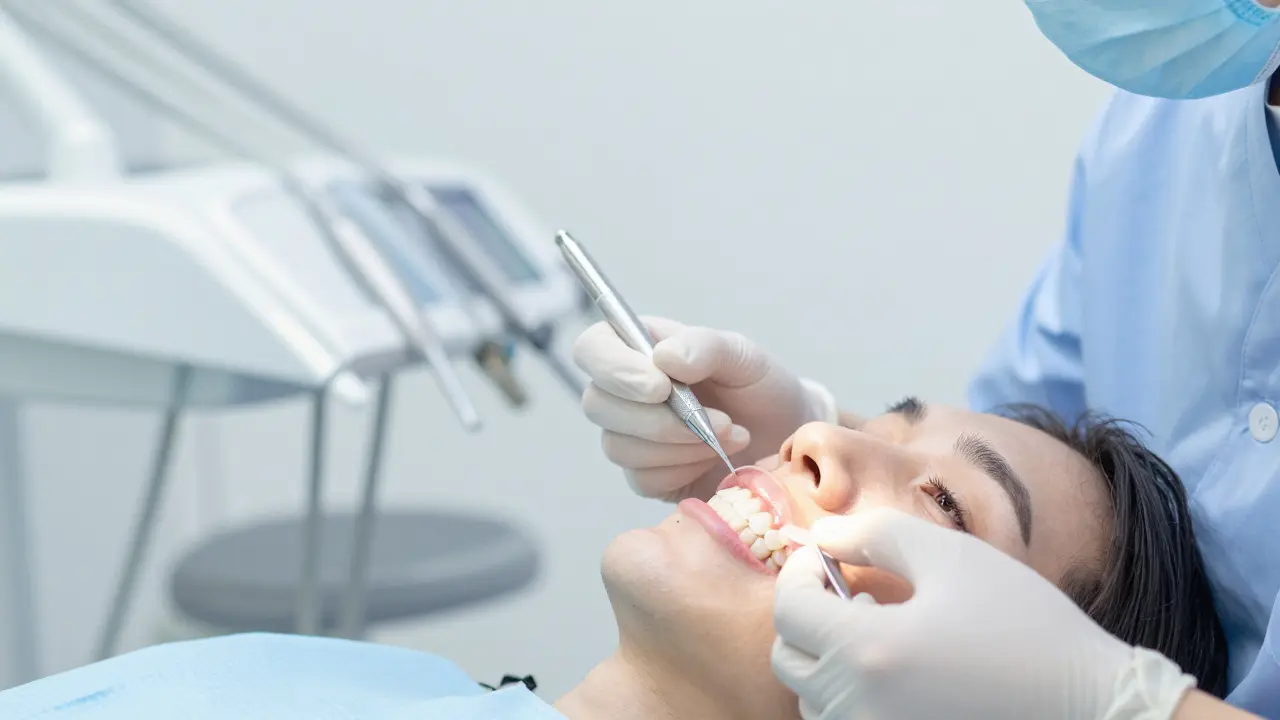 Lékař aplikuje estetickou keramickou obložku na přední zub.